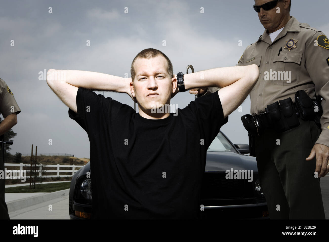 Arrested perpetrator kneeling with hands on head Stock Photo