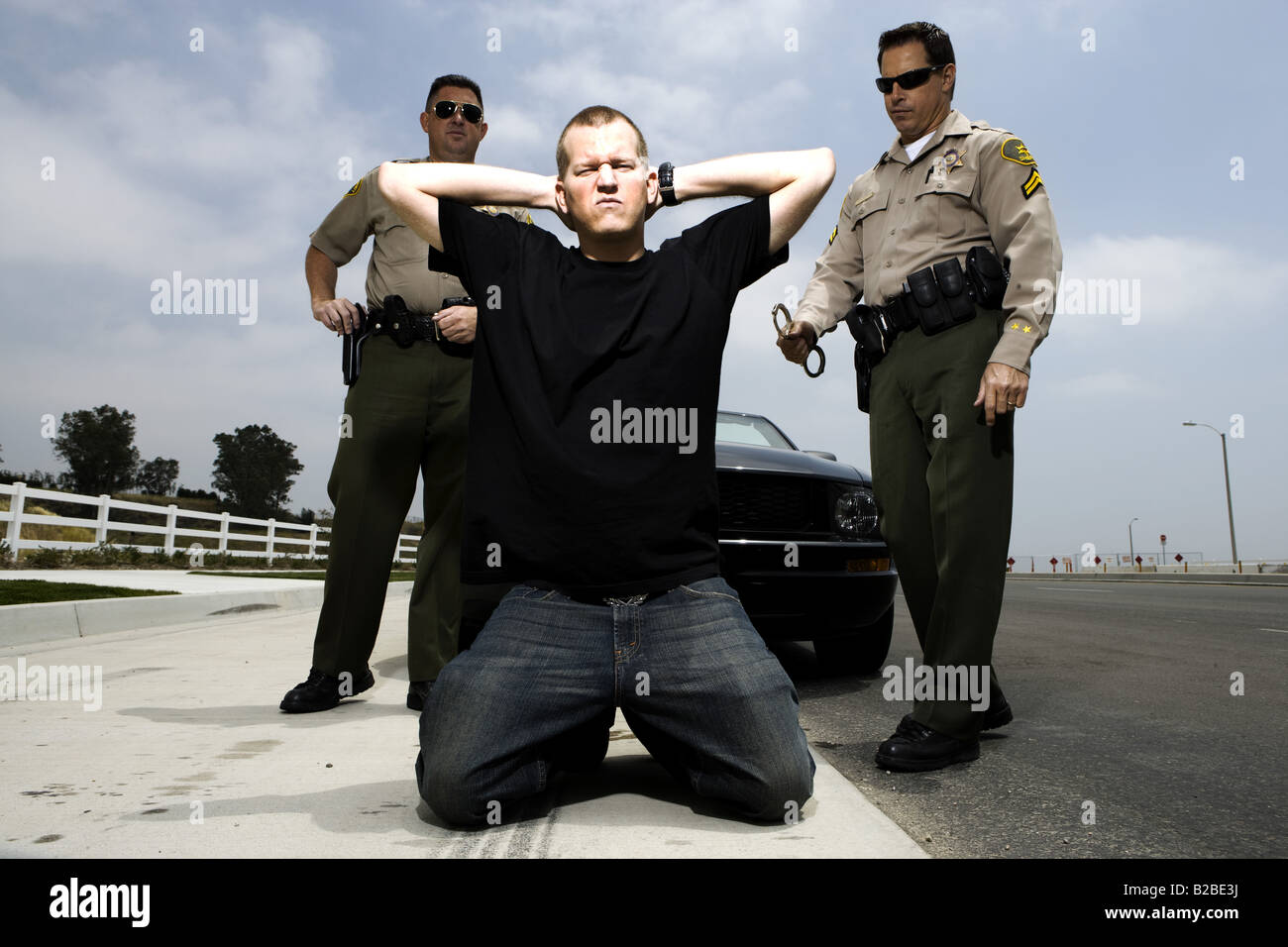 Arrested perpetrator kneeling with hands on head Stock Photo