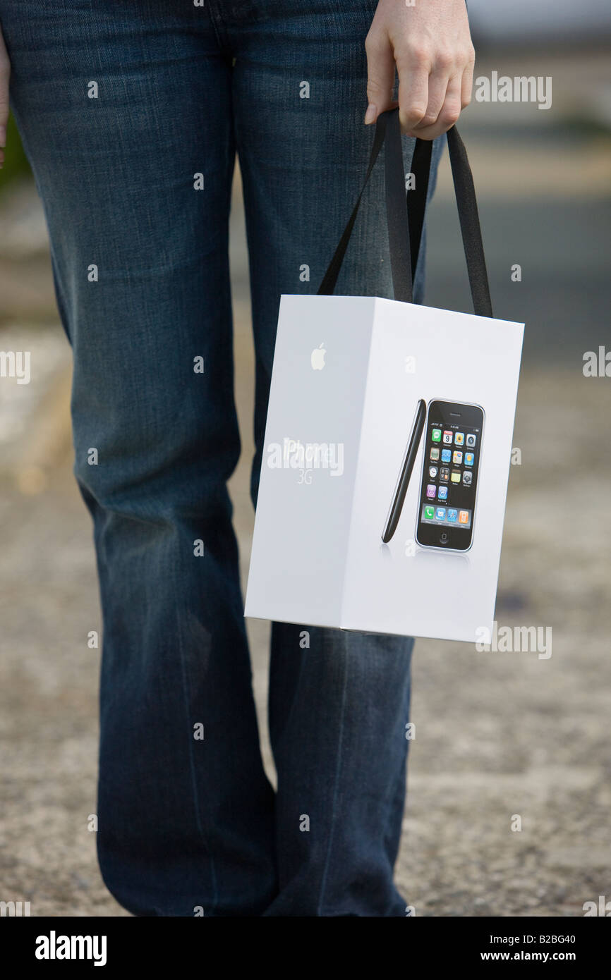 A shopper returns from purchasing an Apple 3G iPhone with product and bag in hand Stock Photo