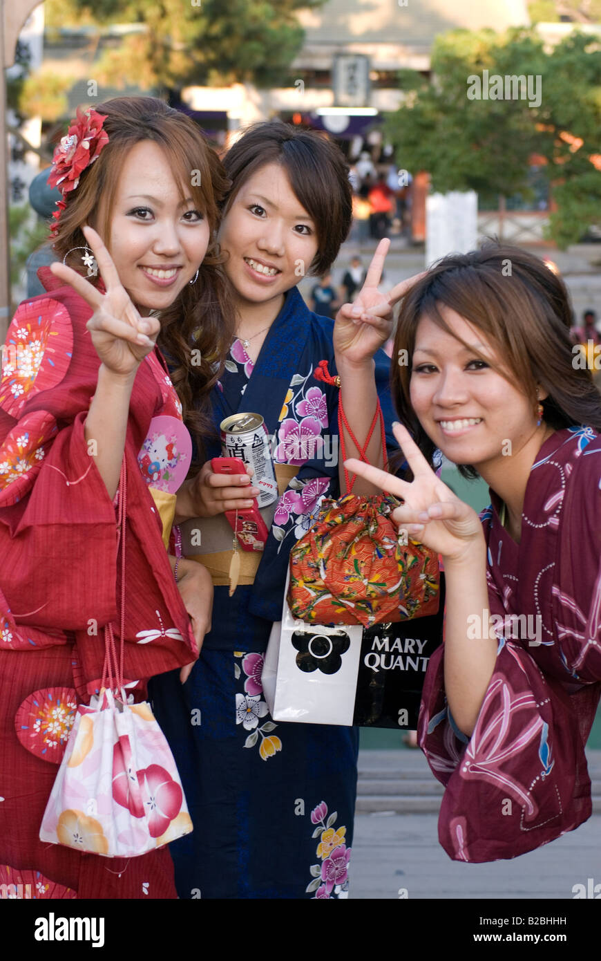 Three happy girls wearing summer yukata robes flash the peace sign when posing for a photograph Stock Photo