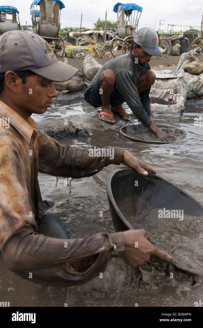 Many slum inhabitants earn their living by recycling industrial waste, these workers are washing poisonous industrial waste for Stock Photo