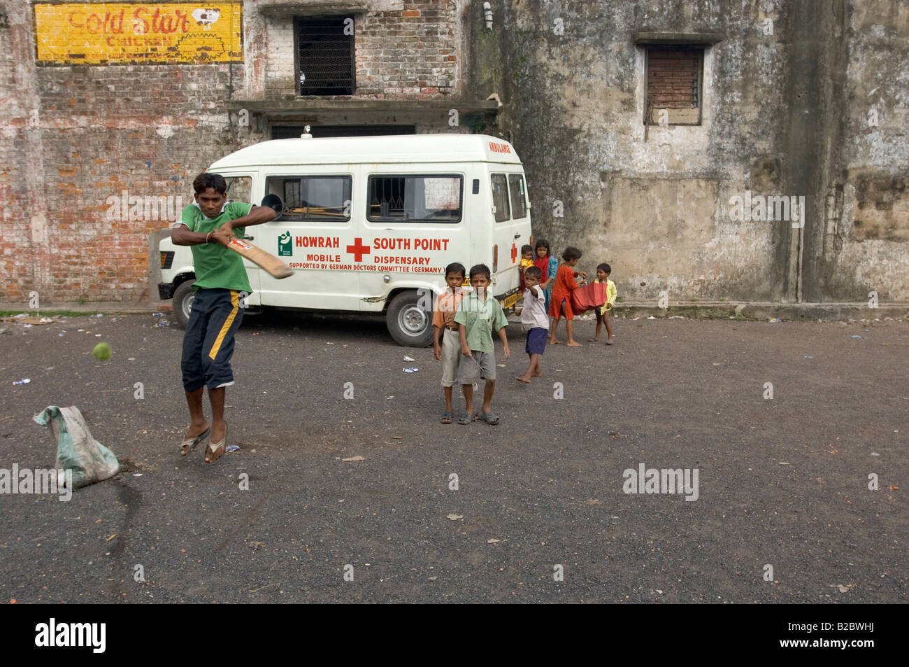 As cricket is the indian national sport, children and teenagers play it everywhere, in this case in front of an ambulance belon Stock Photo