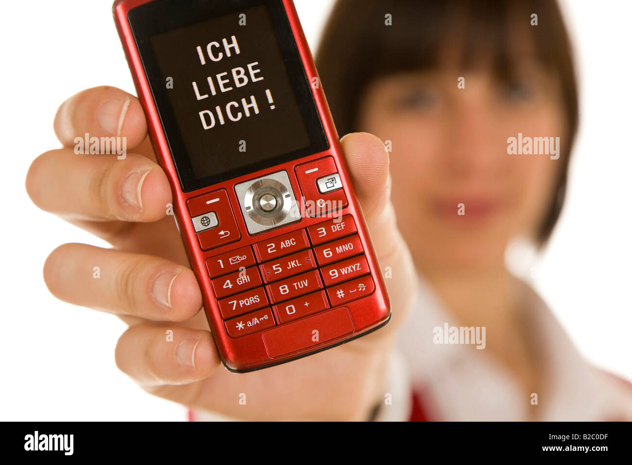 Twenty-year-old woman holding a mobile phone into the camera, with a message on the display, Ich Liebe Dich, I love you Stock Photo