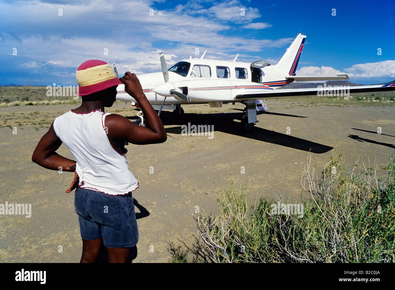Coloured man watching a twin-engine Cessna prepare for takeoff at an unpaved airstrip, airfield, Great Karoo, Cape Province Stock Photo