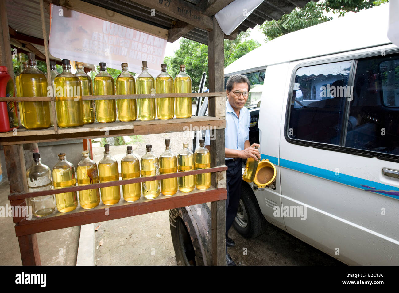 Typical gas station in Asia, petrol stored in glass bottles, car being fueled from glass bottles, Lombok Island, Sunda Islands  Stock Photo
