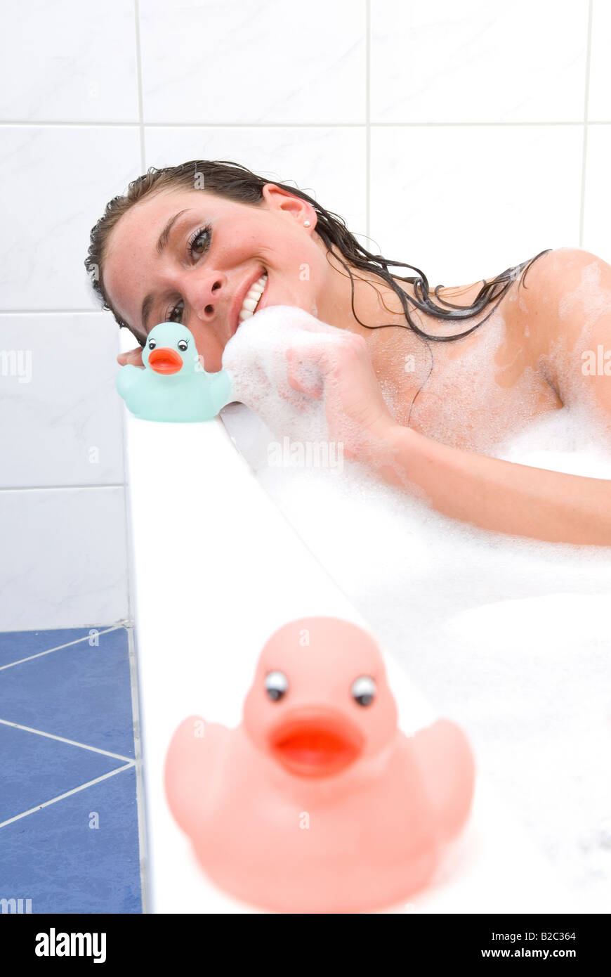 Young woman in the bathtub playing with dabbling ducks Stock Photo