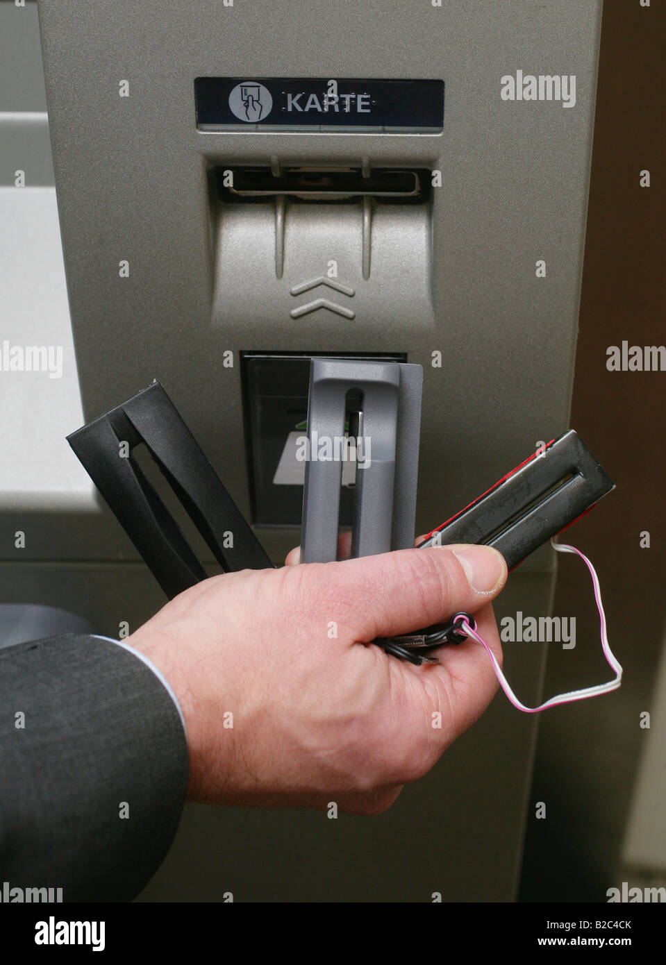 Bank employee demonstrating technical devices used by criminals to spy out numbers and pin codes of bank cards at an ATM machine Stock Photo