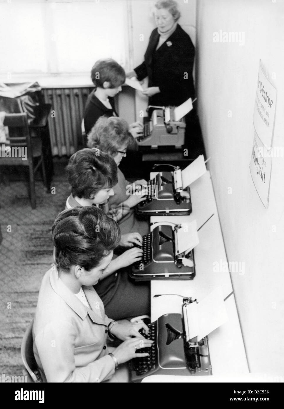 Four women sitting at typewriters, historic picture from about 1960 Stock Photo