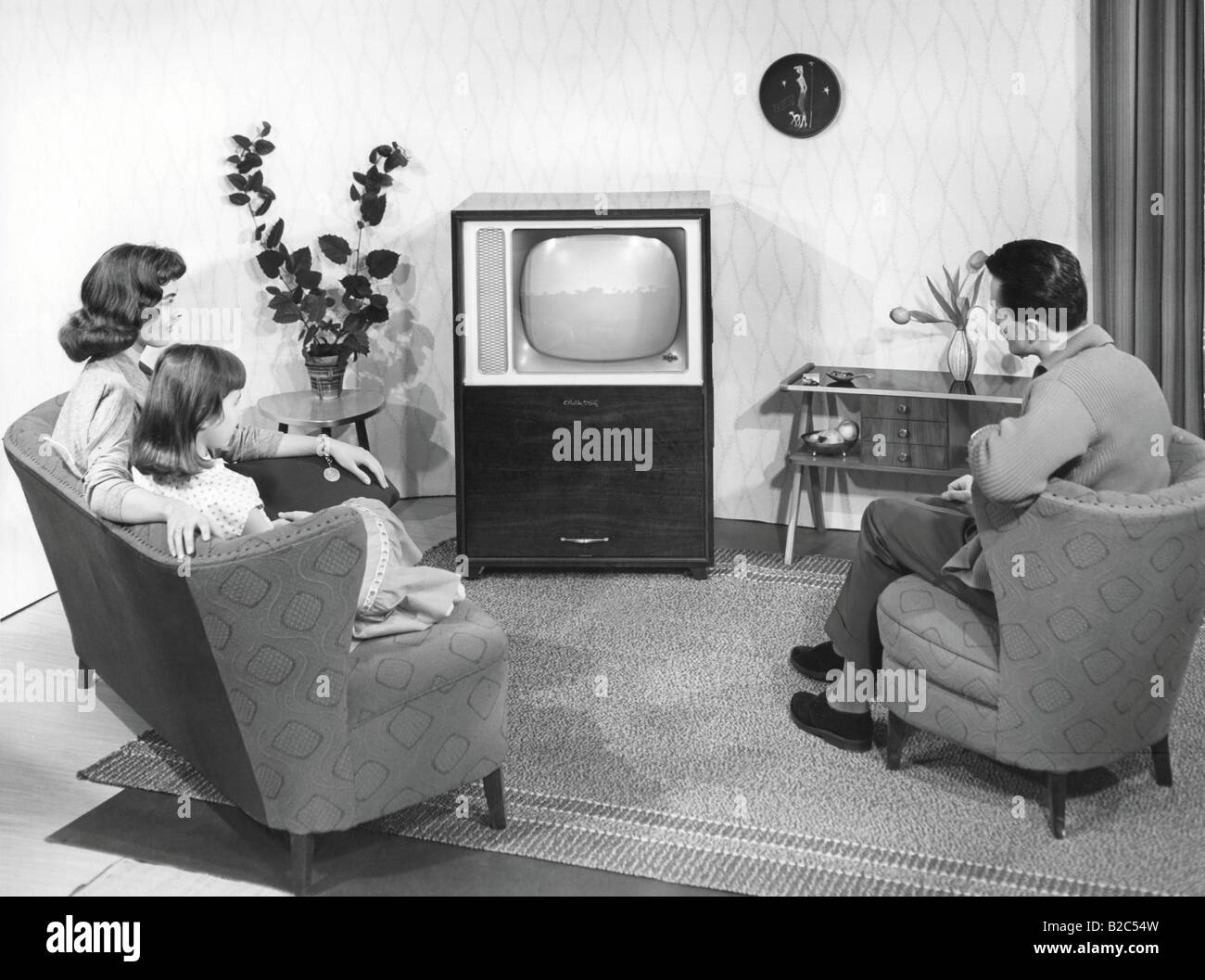 A model family in front of the television in a model living room, historical photo, circa 1955 Stock Photo