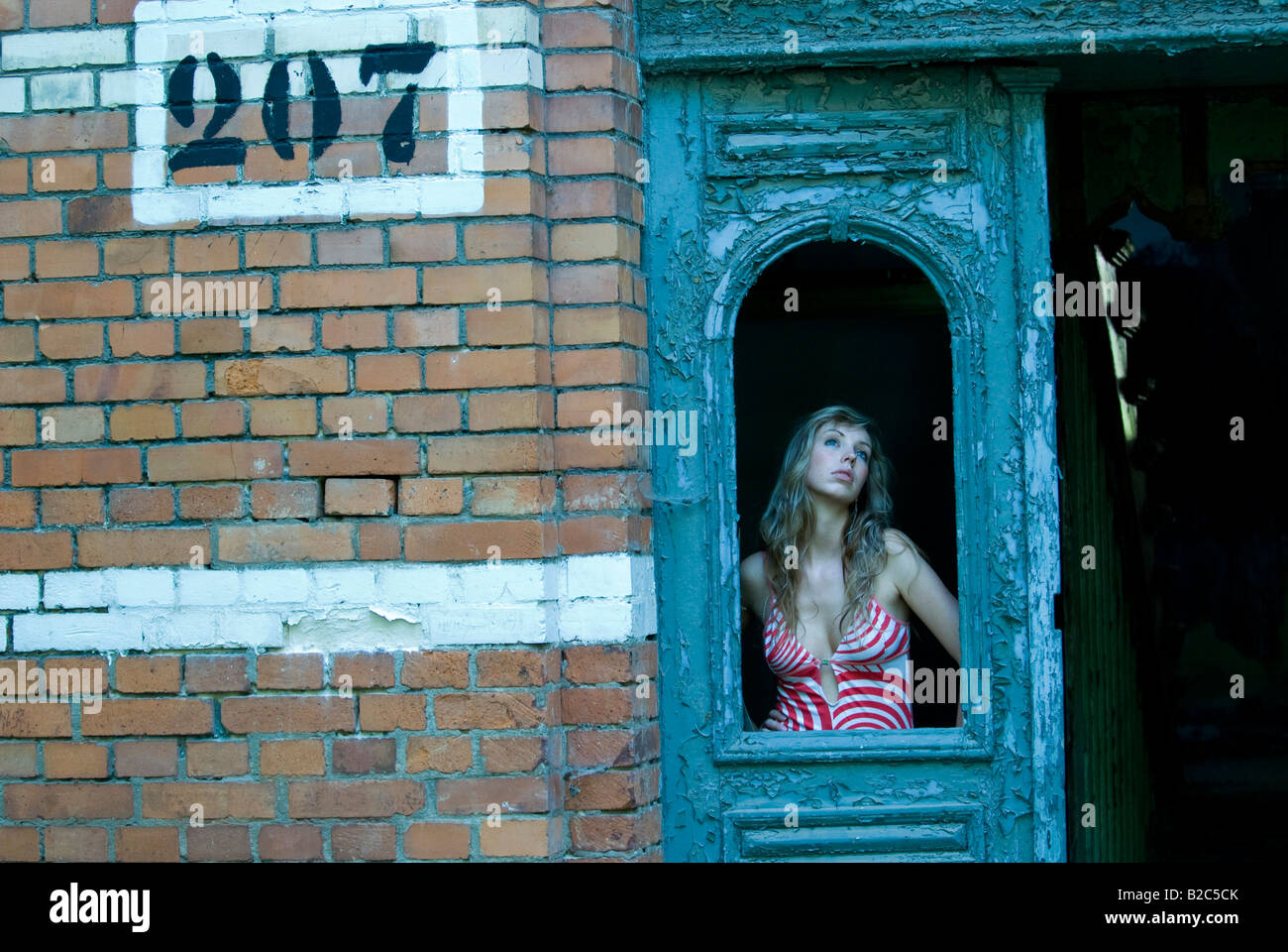 young woman posing in an entrance door of a desolate vacant house Stock Photo