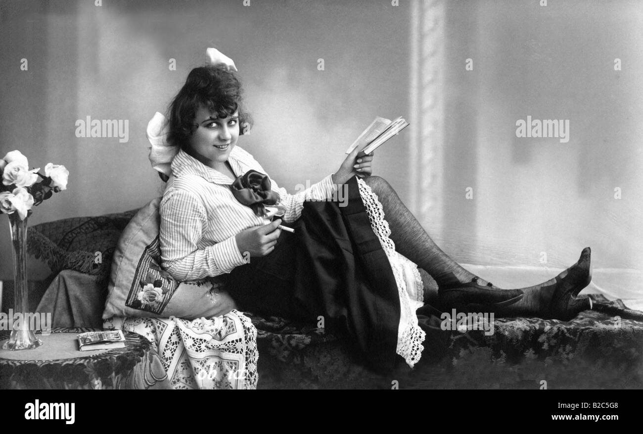 Woman reading and smoking on a divan, historic picture from about 1910 Stock Photo