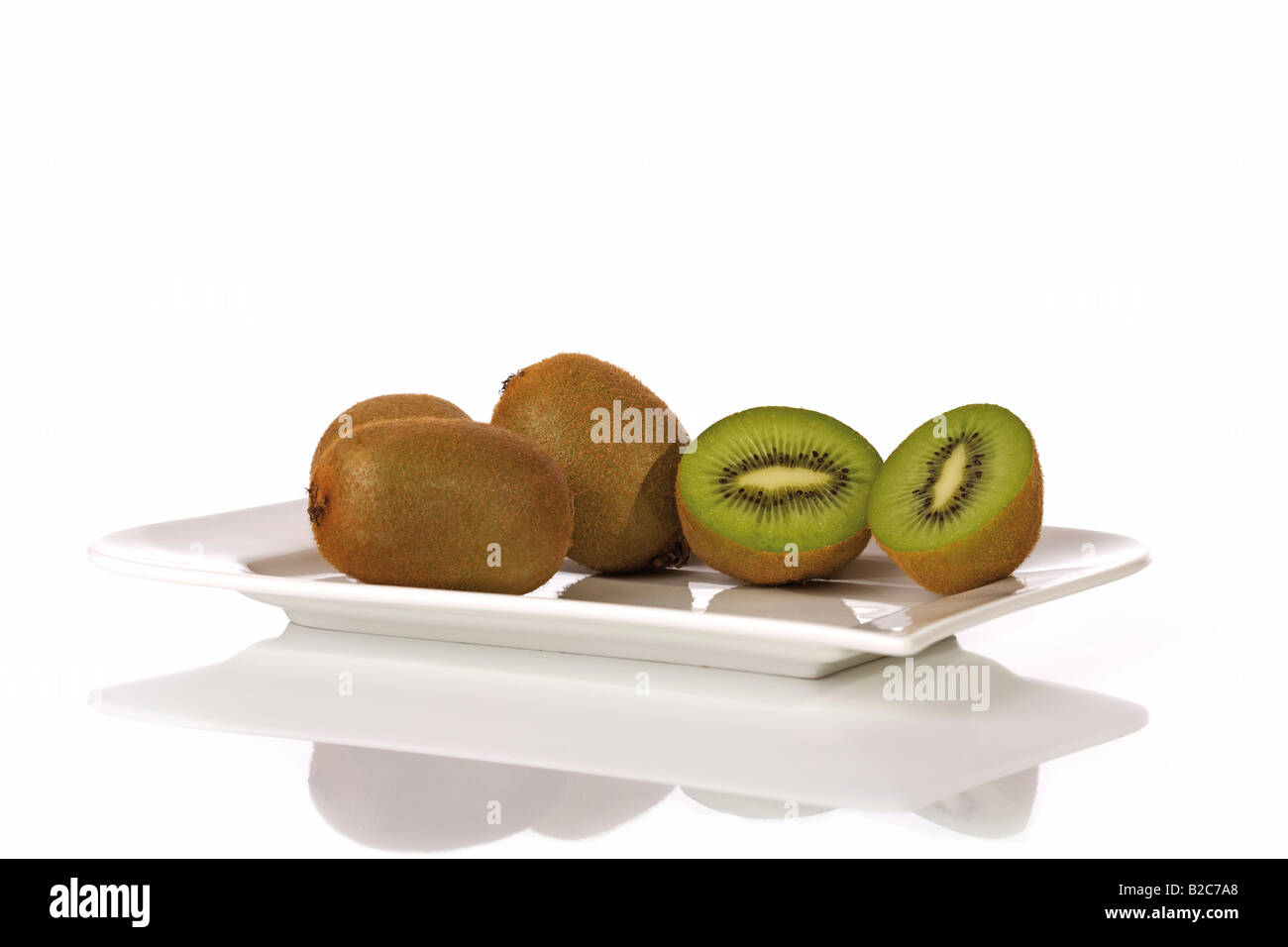 Kiwi (Actinidia deliciosa) cut into halves, on a plate Stock Photo