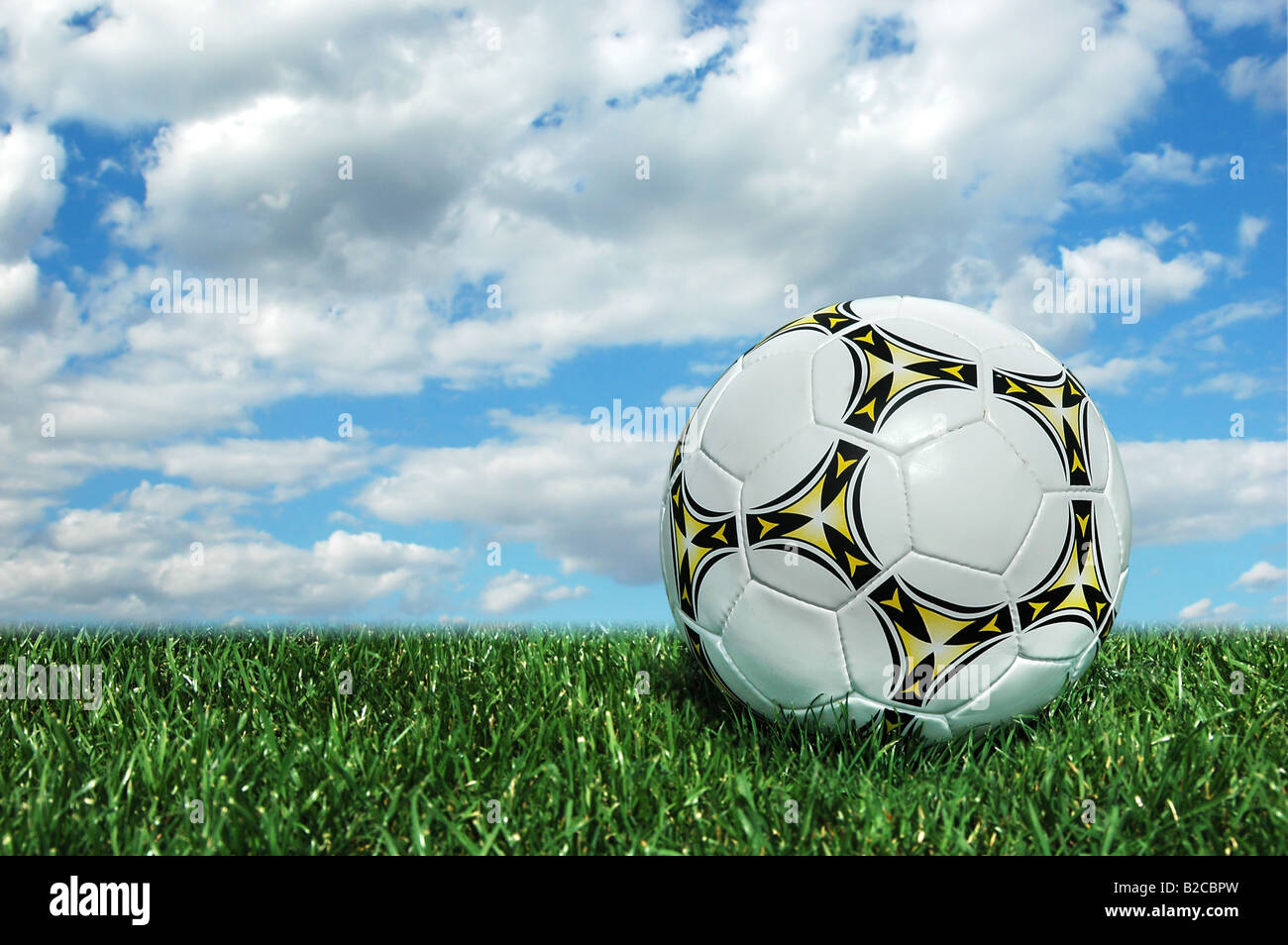 Soccer ball on grass field and a bright sky as background Stock Photo