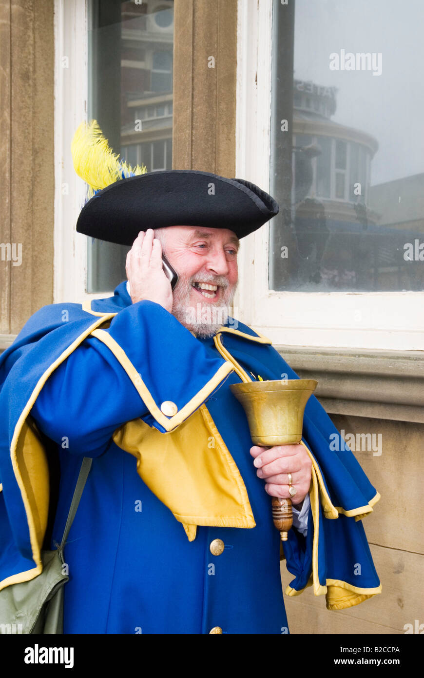 Town Crier takes a break from his verbal announcements and bell ringing to to answer his mobile