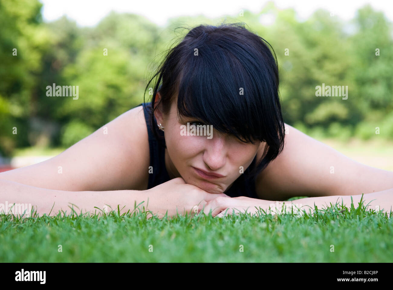 young female athlete lying exhaustedly on a lawn, training break Stock Photo