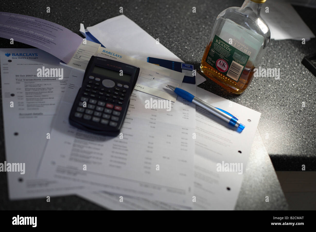 Bills and statements against a bottle of brandy - money worries Stock Photo