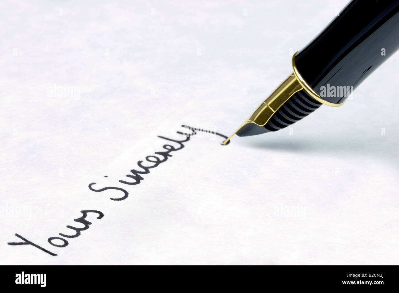 Yours Sincerely written on watermarked textured paper using a gold nibbed fountain pen Focal point is on the text Stock Photo