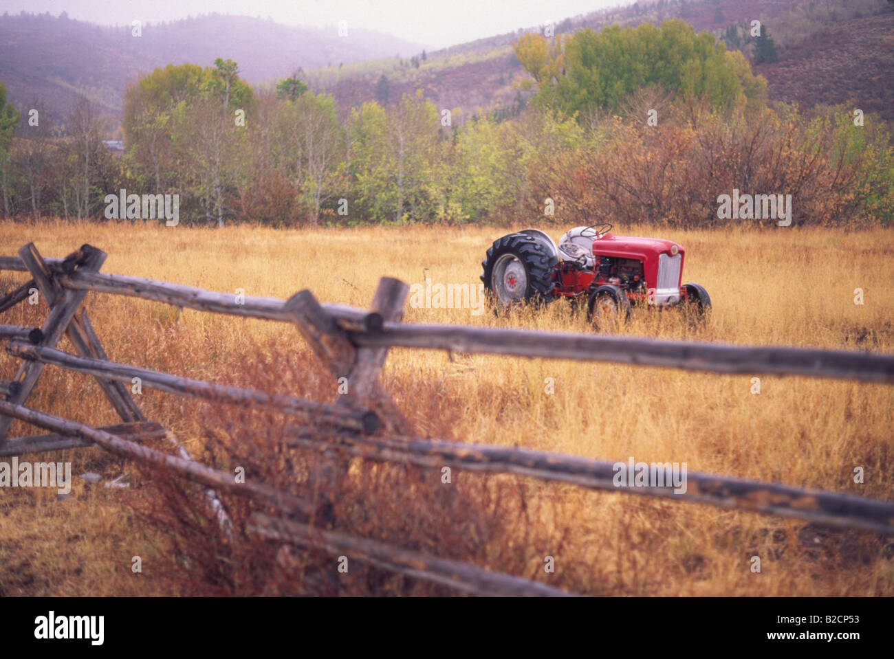 Farm Tractor sit in a field behind a fence Stock Photo - Alamy