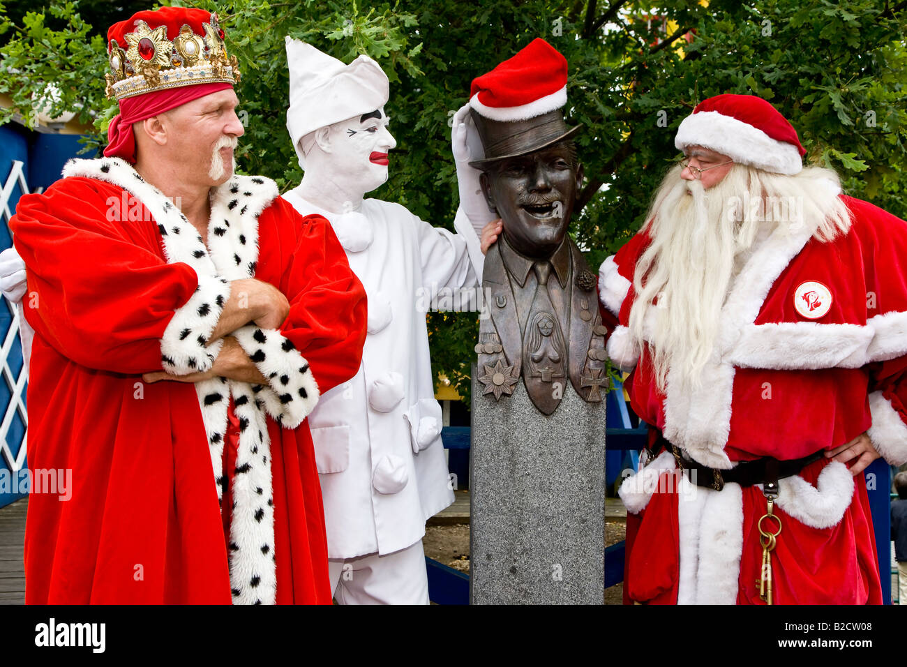 Santas and Pjerrot in front of the statue of the street entertainer professor Tribini in Denmark Klampenborg Bakken Stock Photo