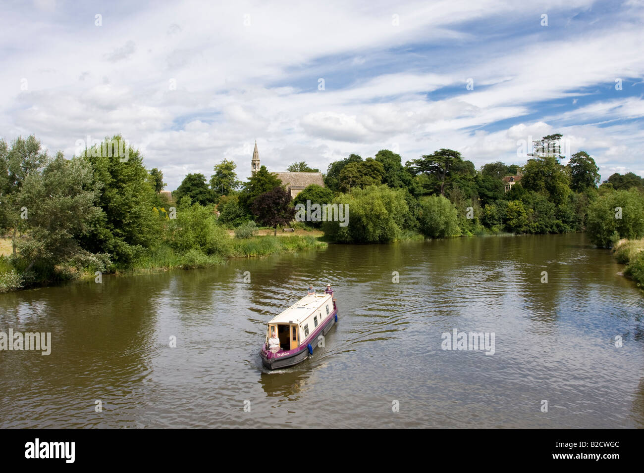 A Narrow Boat Passes Clifton Hampden Travelling towards Oxford with a woman sitting in the bow Stock Photo