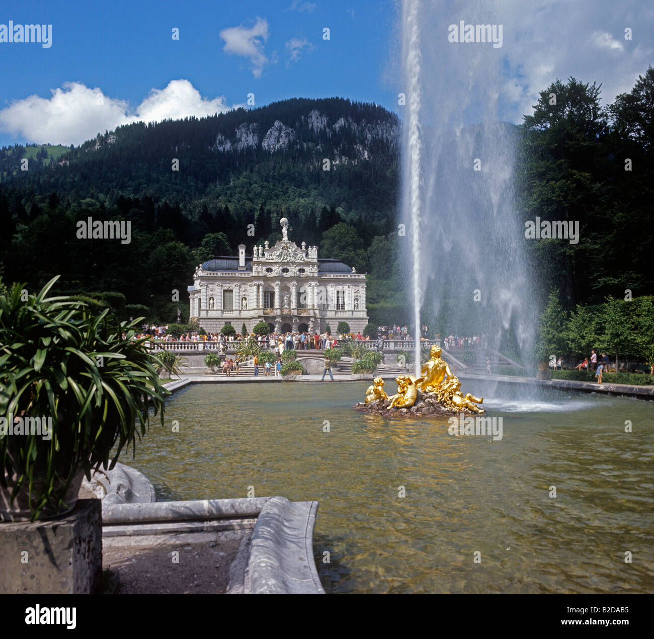 Linderhof Castle with visiting tourists and powerful jet of water from gilded fountain Stock Photo