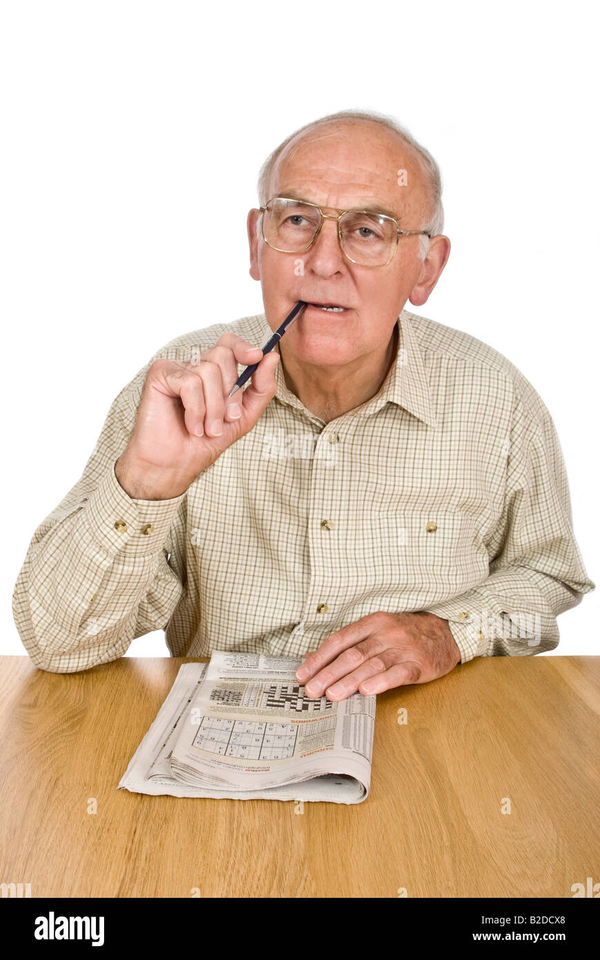 Vertical portrait of an elderly gentleman concentrating over the Sudoku puzzle in his daily newspaper Stock Photo