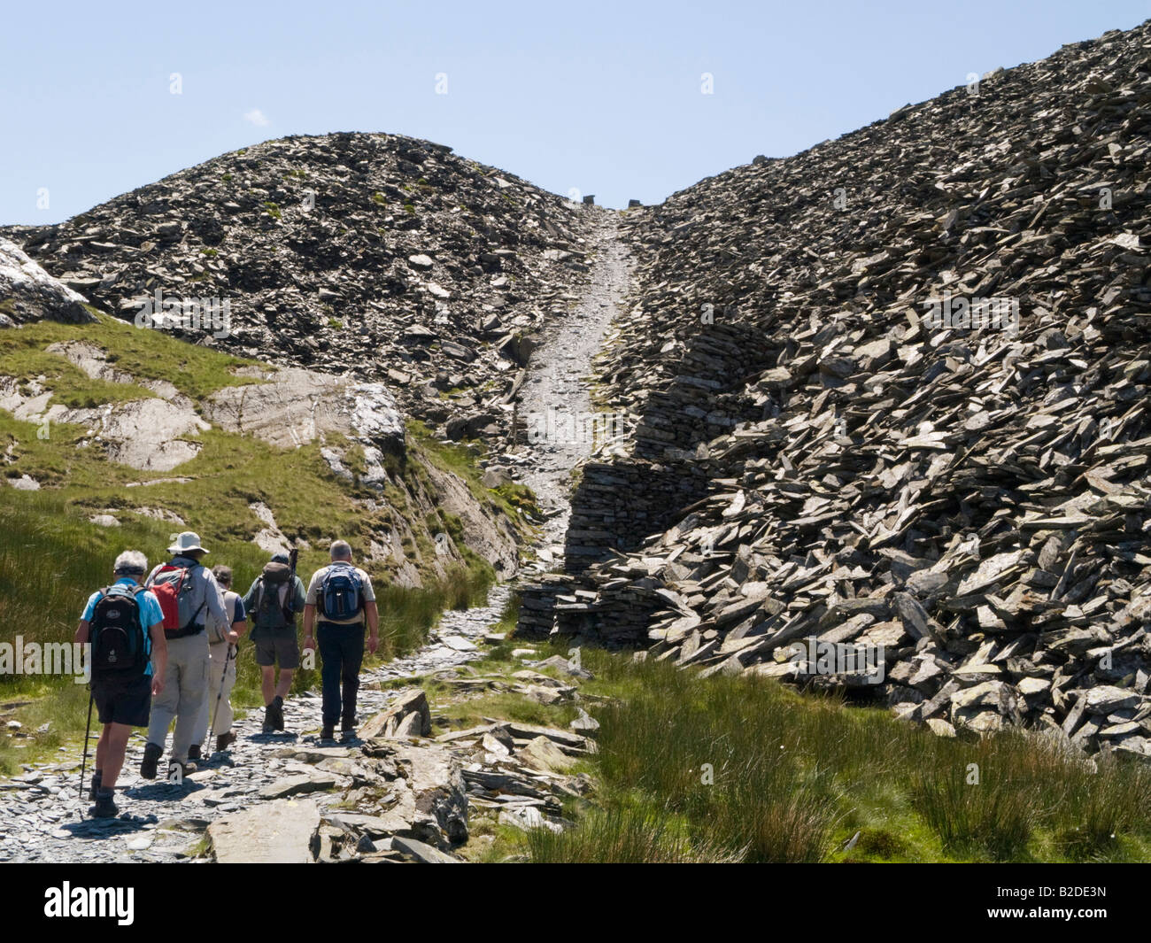 Group of walkers hiking through abandoned disused slate quarry below Moelwyn Mawr in Cwm Croesor Snowdonia National Park North Wales UK Britain Stock Photo