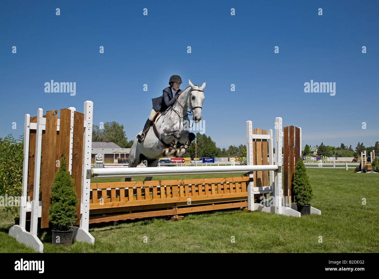 A rider and her hunter jumper horse take a jump in a competition ring
