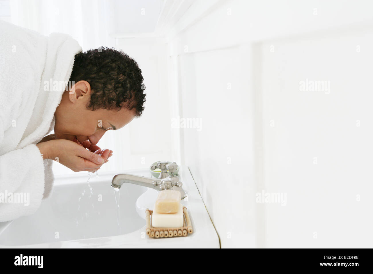 African American woman washing face in sink Stock Photo Alamy