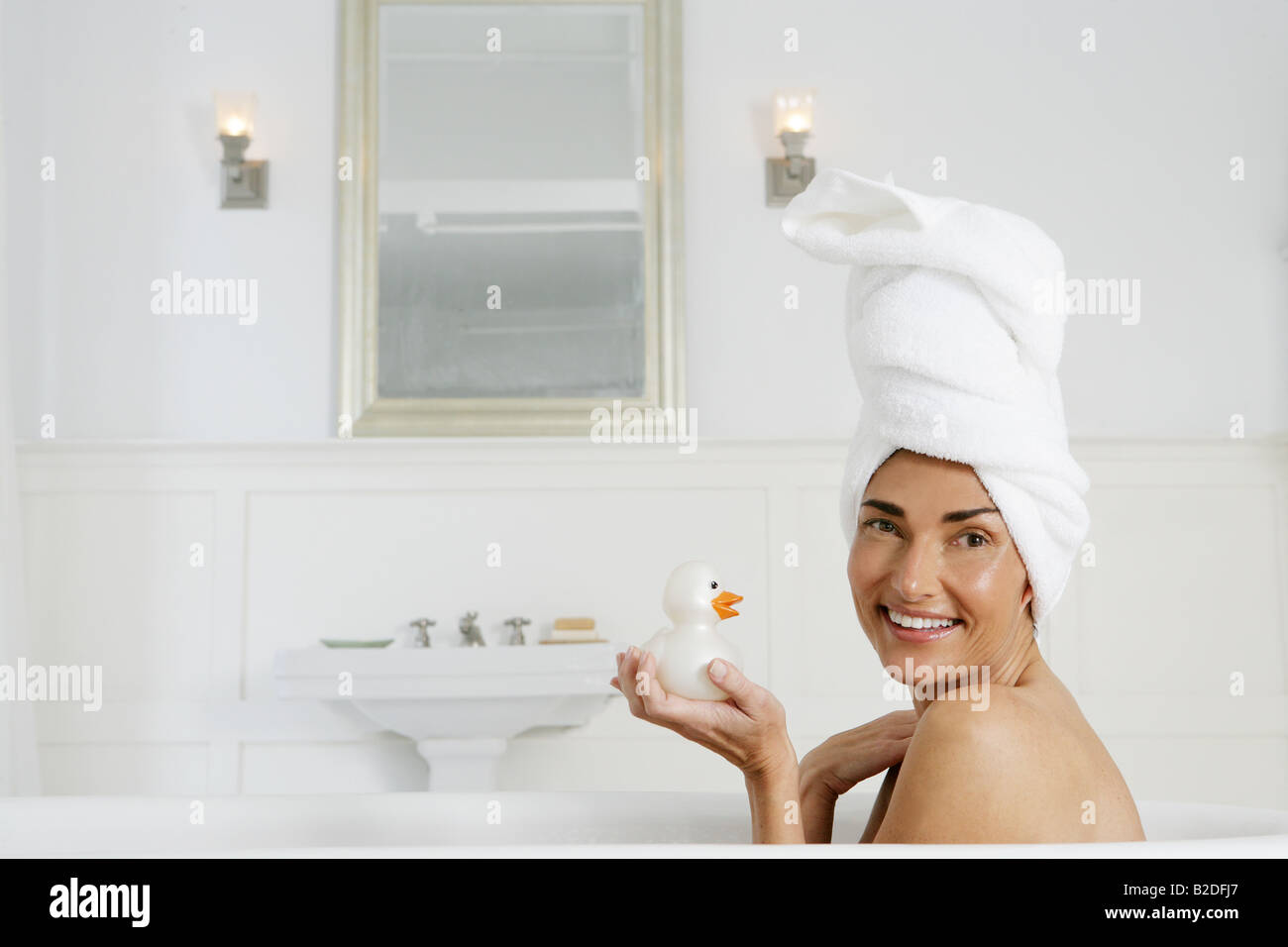 Woman in bathtub holding rubber duck. Stock Photo