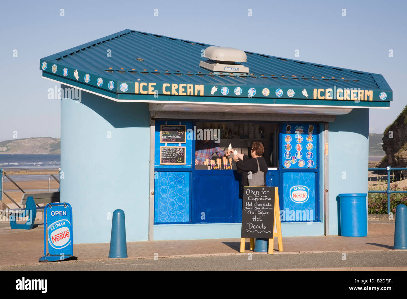 Person buying ice cream from a kiosk on seafront of seaside resort in summer. Benllech Anglesey North Wales UK Stock Photo