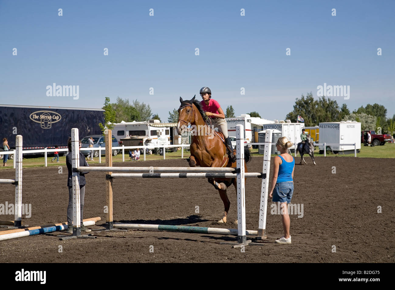A rider and her hunter jumper horse take a practice jump in a practice