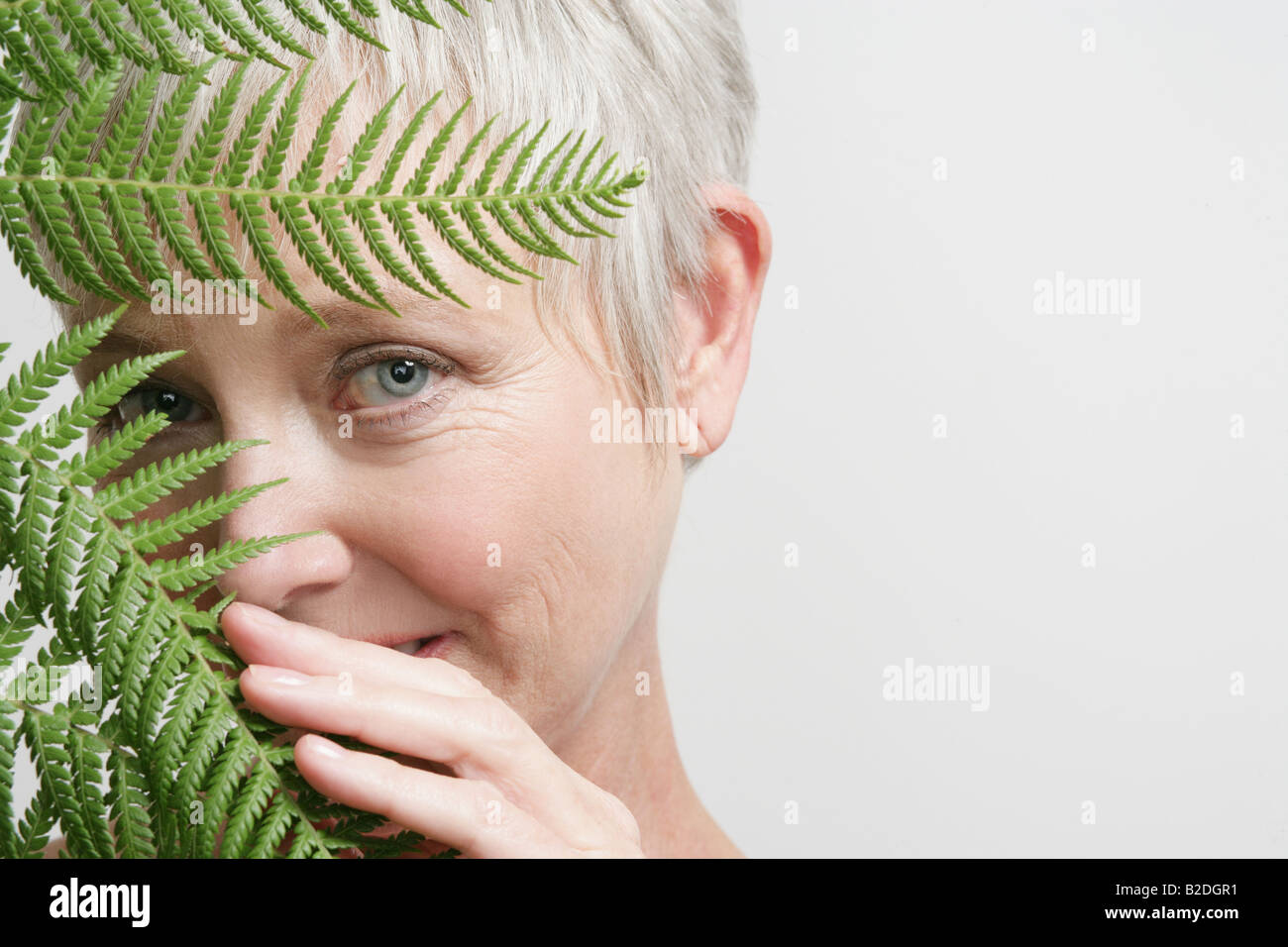 Mature woman behind leaves Stock Photo - Alamy