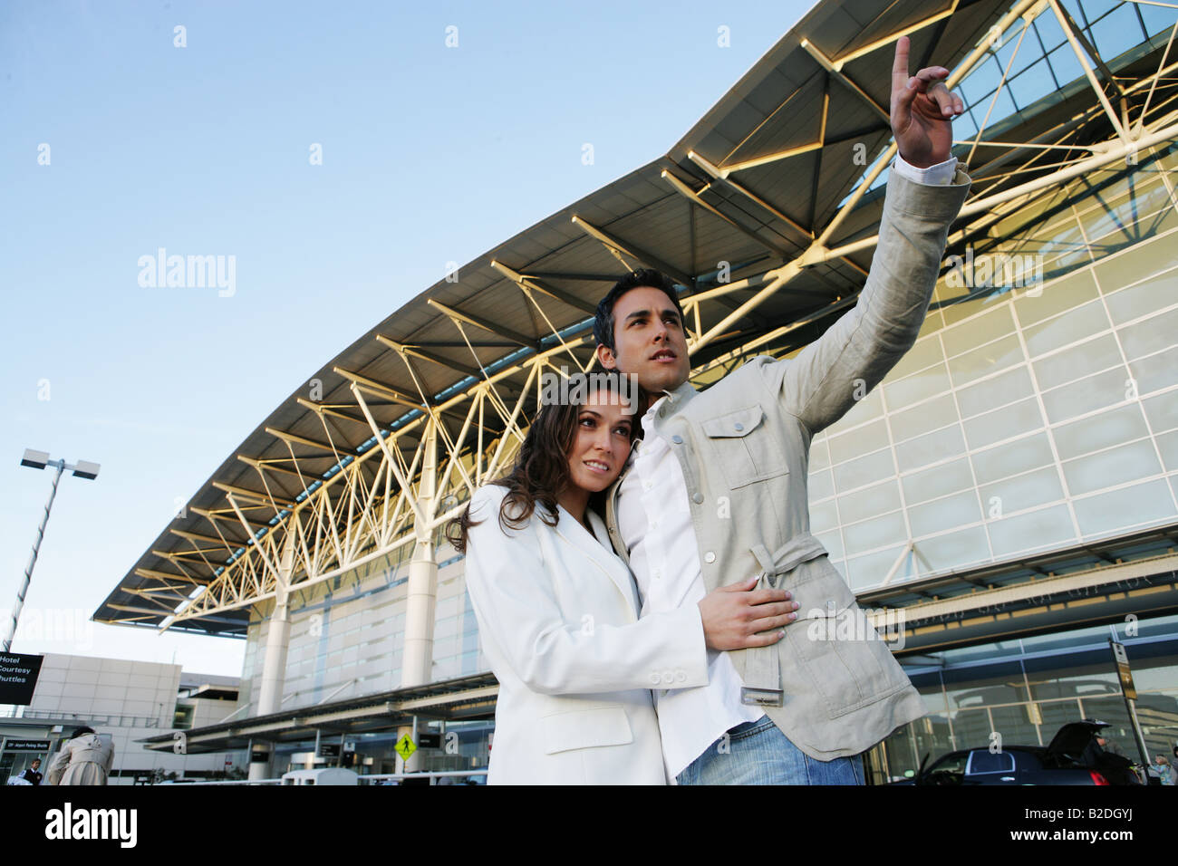 Young couple hailing taxi at airport. Stock Photo