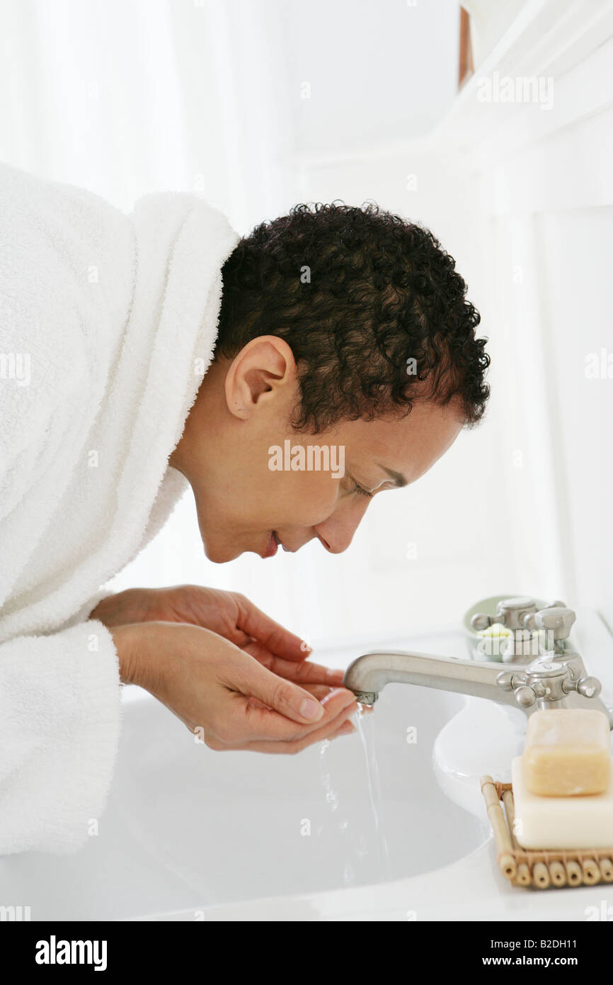 African American woman washing face in sink Stock Photo Alamy