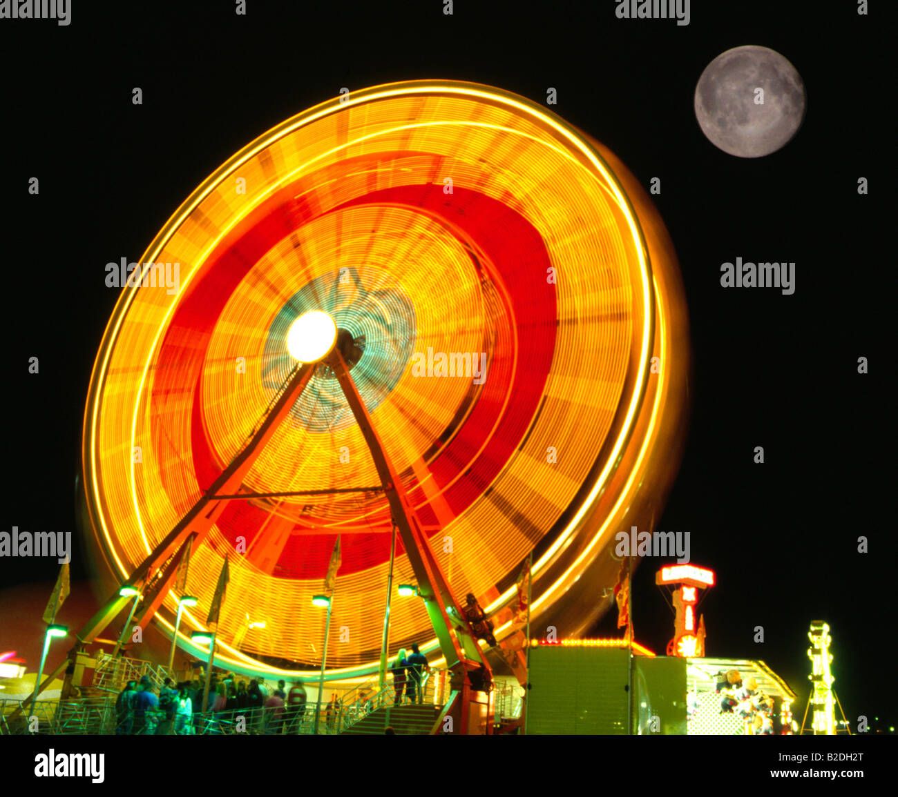 Spinning Ferris Wheel and Full Moon Rising Stock Photo