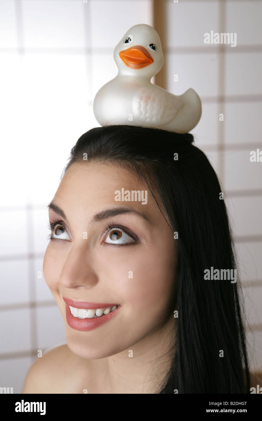 Young woman balancing rubber duck on head. Stock Photo