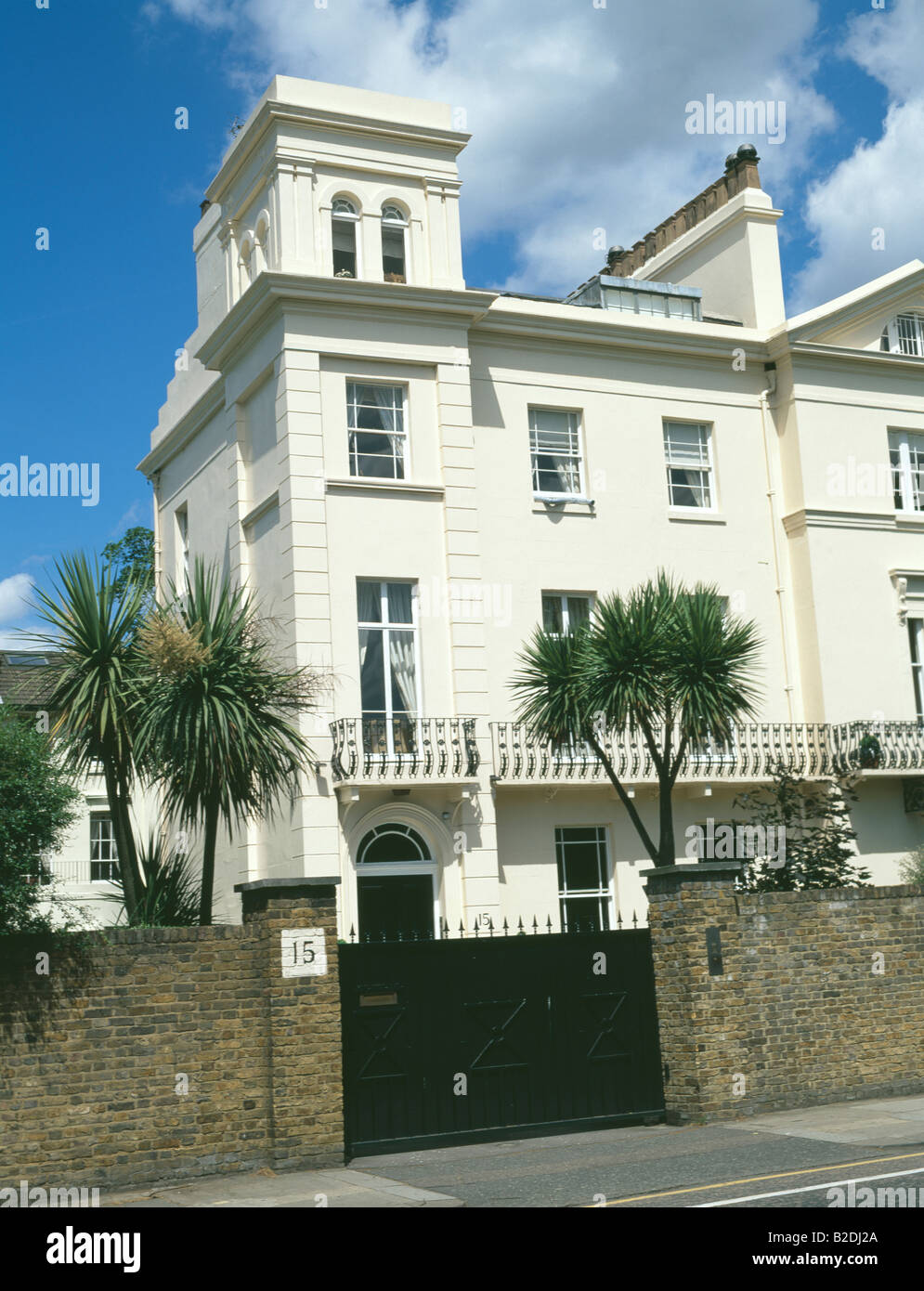 Black gates and brick wall in front of white Regency terraced house in