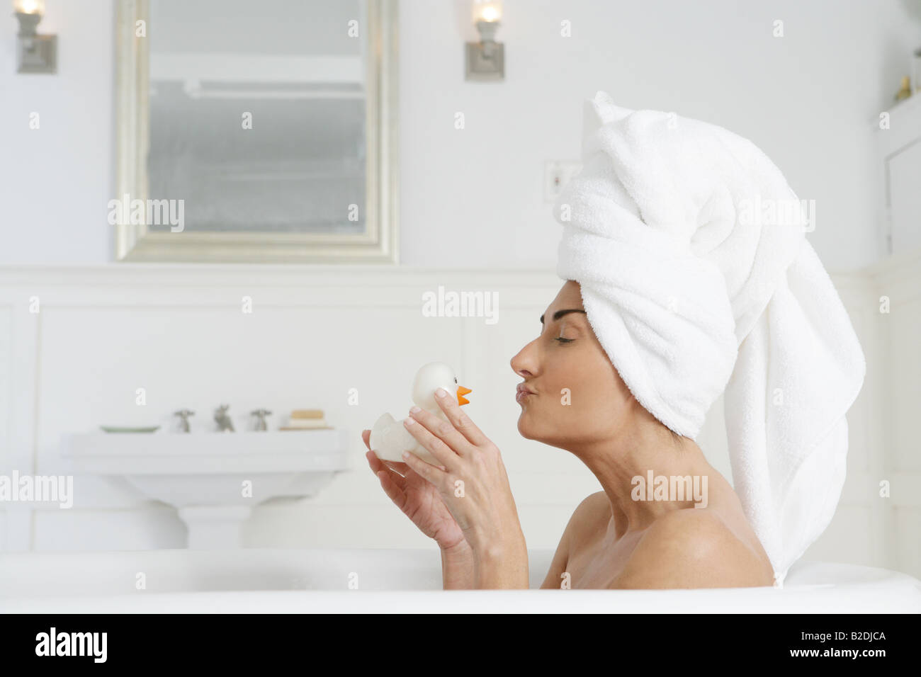 Woman in bathtub kissing rubber duck. Stock Photo