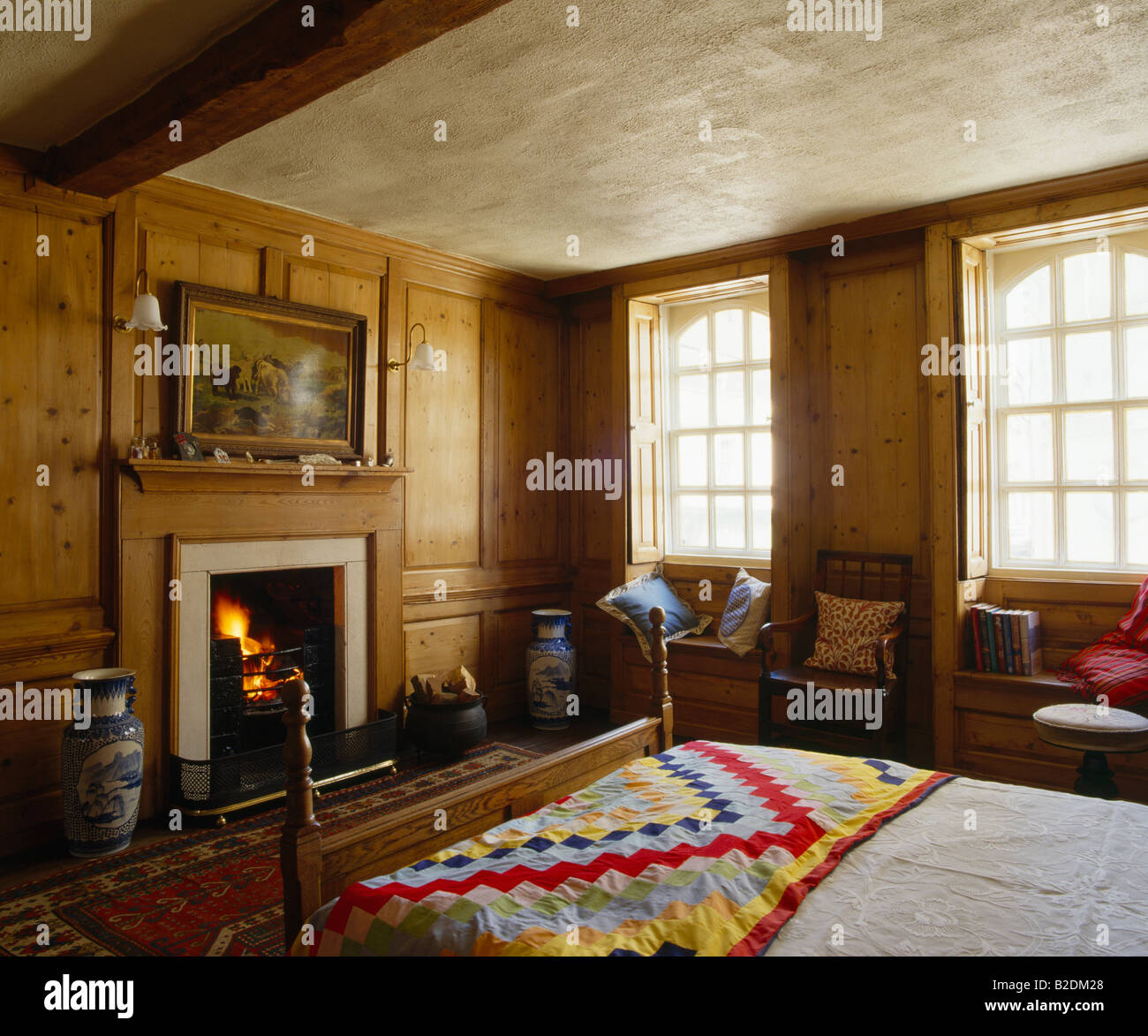Patchwork quilt at the end of bed in paneled bedroom with
