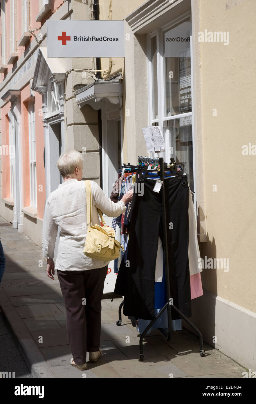 Woman looking at second hand clothes on rack outside charity shop Brecon Wales UK Stock Photo