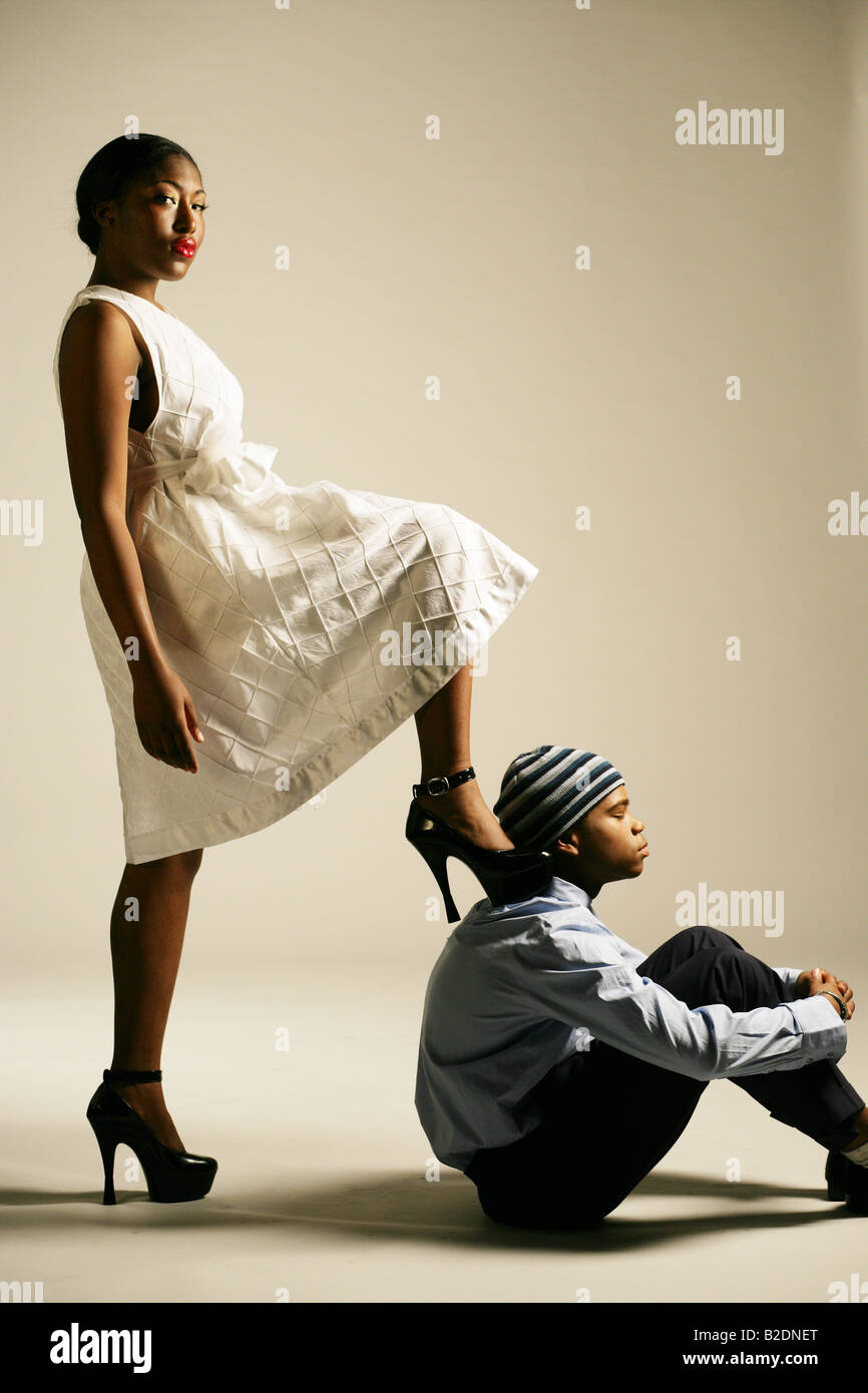Young African American woman stepping on man, studio shot Stock Photo -  Alamy