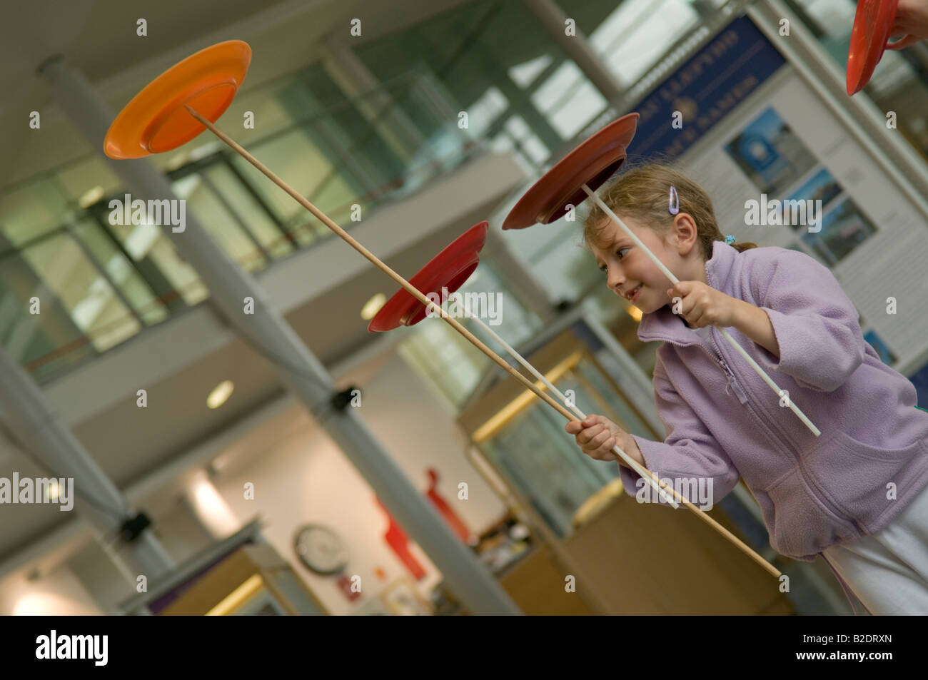 young girl spinning plates on sticks circus skills workshop National Maritime Museum of Wales Swansea UK Stock Photo