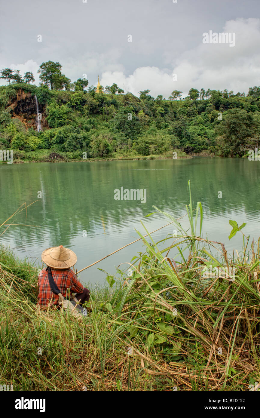 An angler in Mae Sot Thailand Fishing with a watefall and a golden stupa above the fishing pond Stock Photo