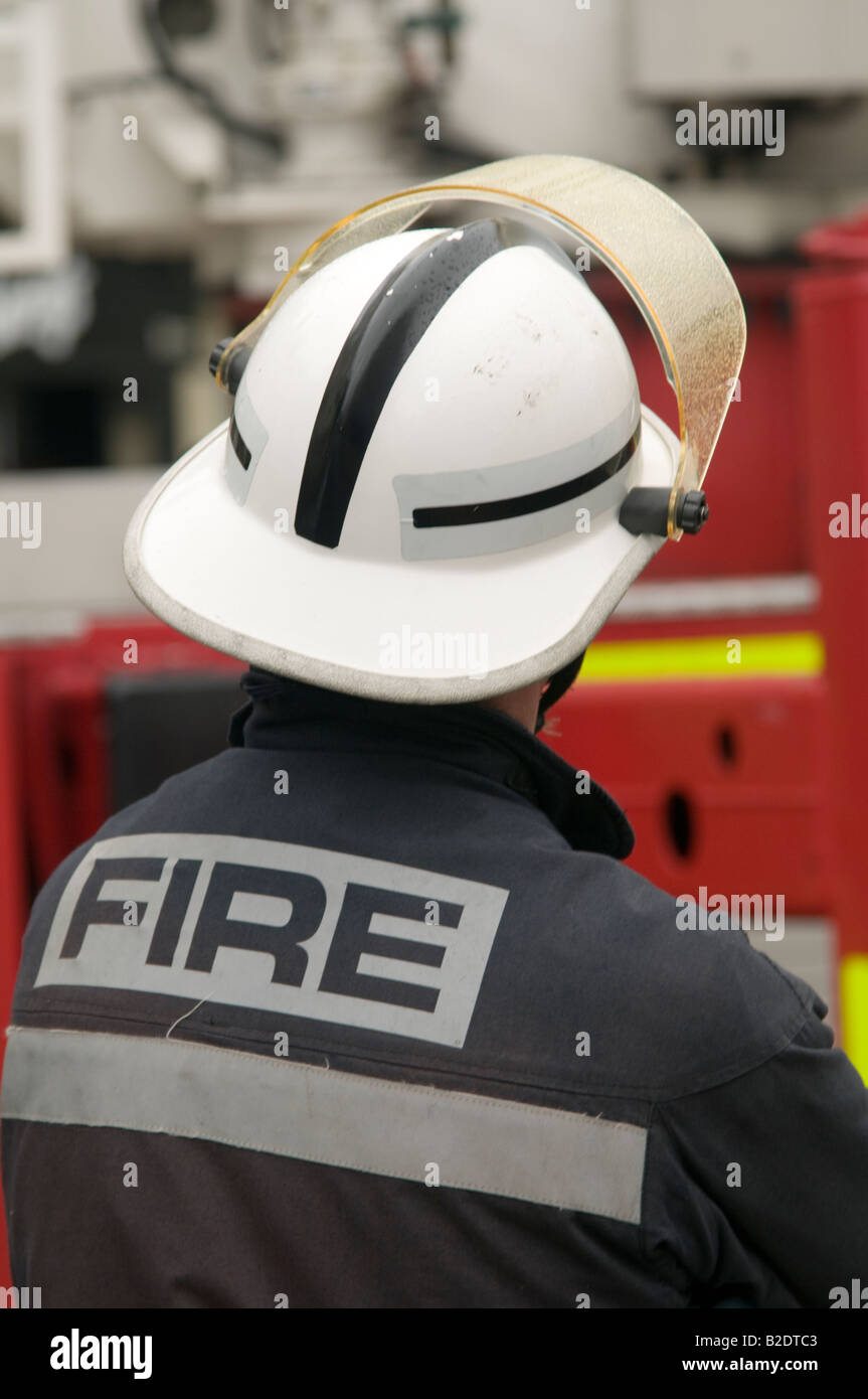 Fire brigade officer viewed from behind, wearing white hard hat safety helmet Stock Photo