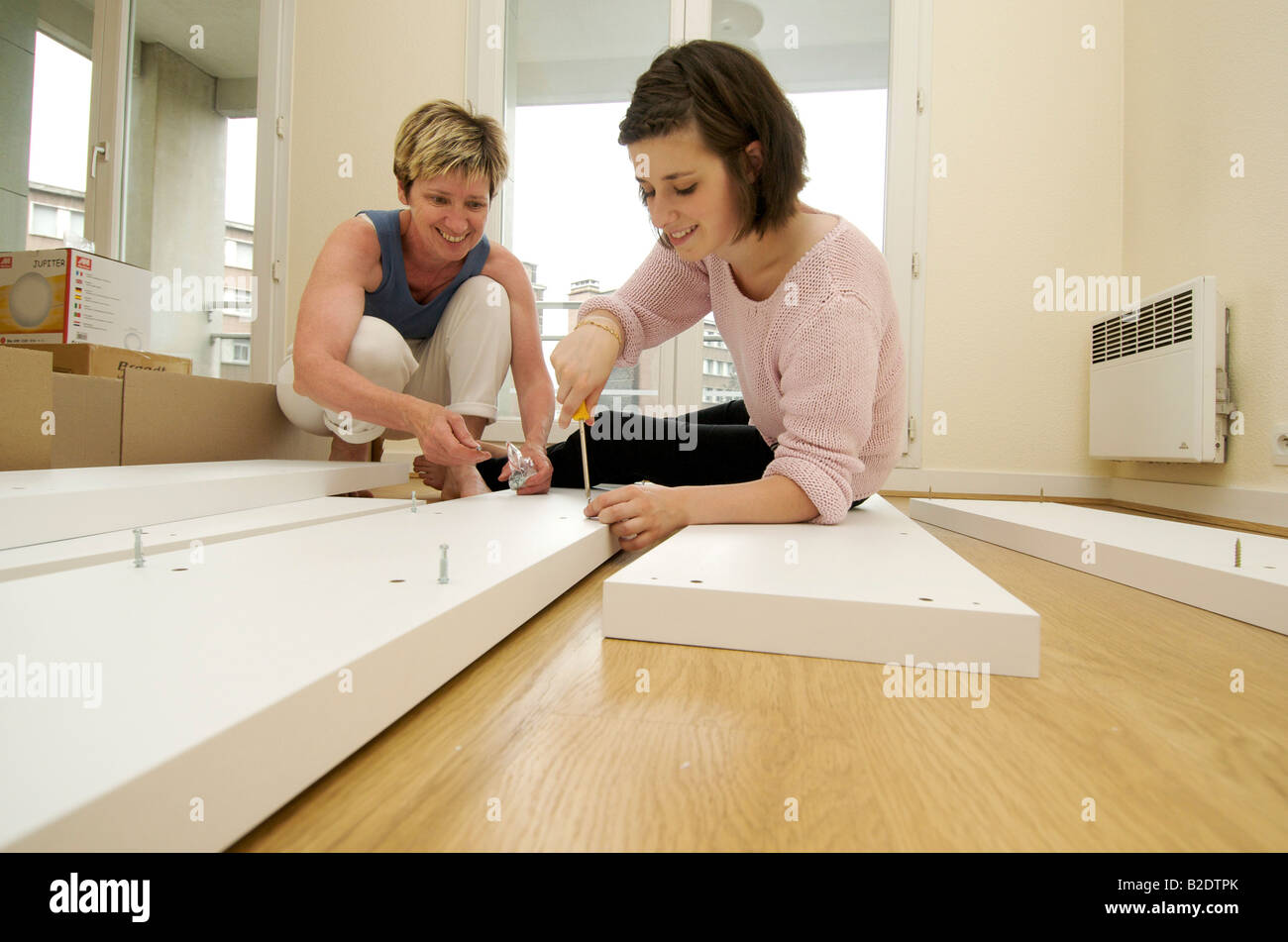 Moving house mother and daughter assemble furniture in a new home
