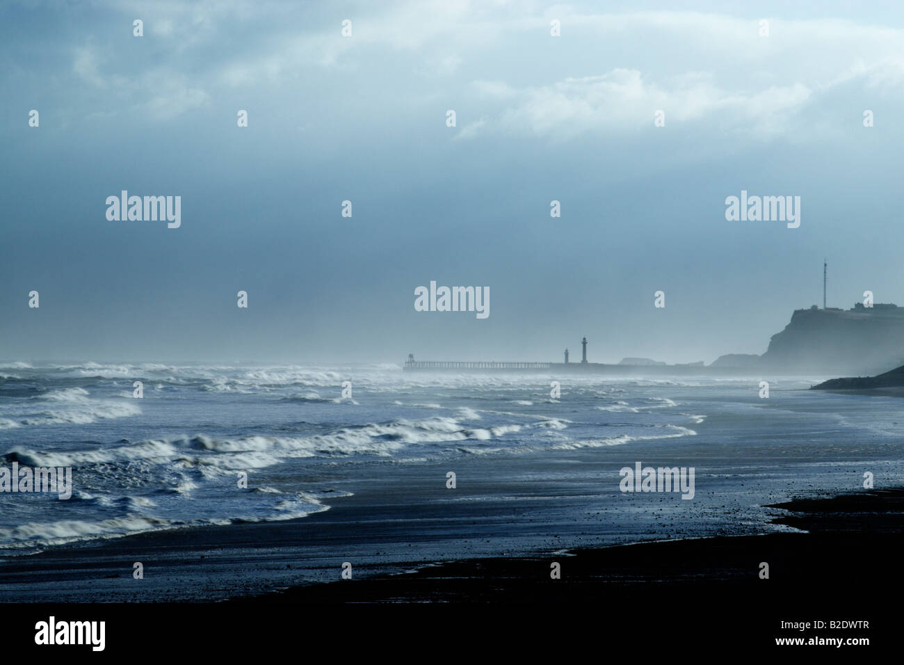 View along Sandsend beach towards Whitby pier during storm surge conditions Stock Photo