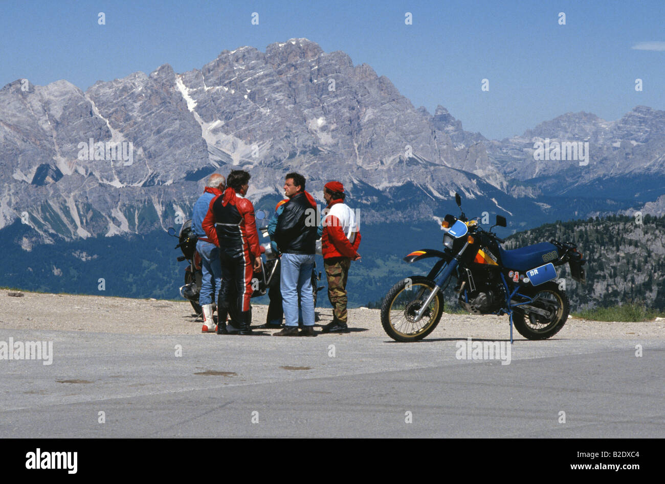 Group of motorcyclists rest and talk at the summit of Passo Giau in the Dolomite mountains of northern Italy Stock Photo