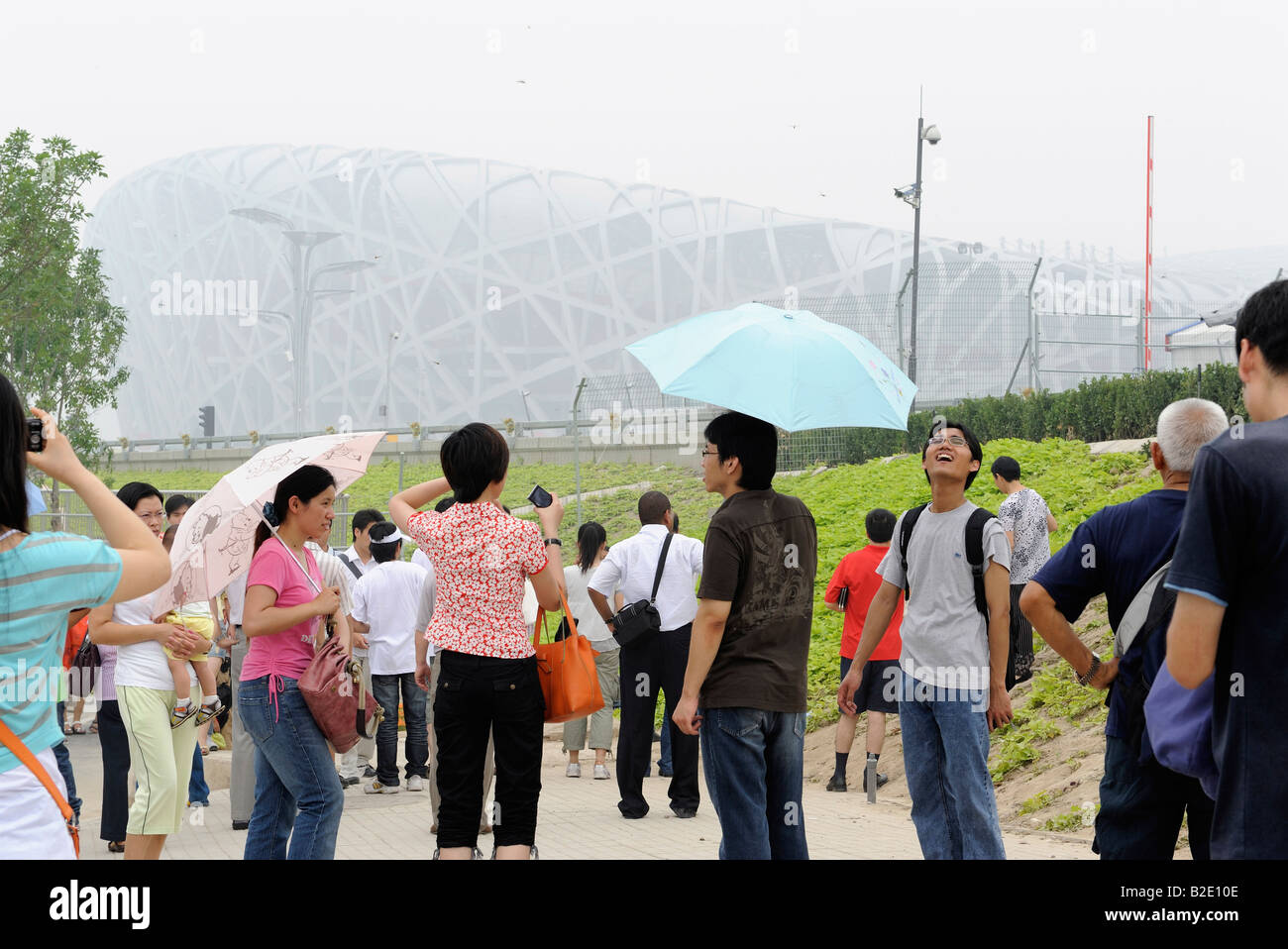 Chinese tourists look at National Stadium in a haze in Beijing, China. 27-Jul-2008 Stock Photo