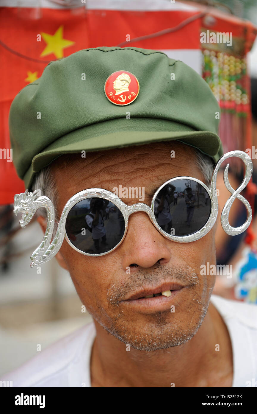 Chinese fan with Mao badge and eyeglasses shaping 2008 and dragon outside the Olympic Green in Beijing. 27-Jul-2008 Stock Photo